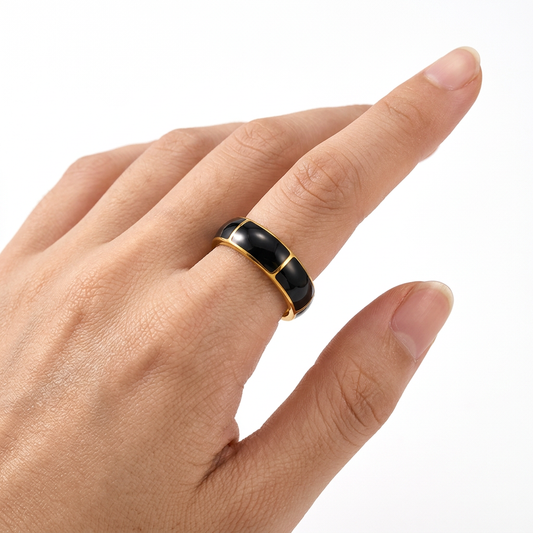Jeden złoto-czarny pierścionek z emalią na dłoni modelki na białym tle