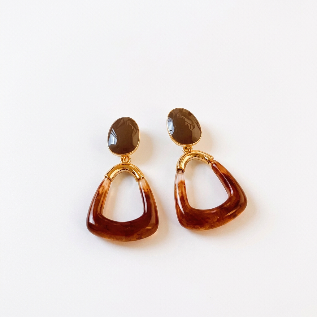 Para brązowych wiszących kolczyków z otwartymi trapezowymi zawieszkami i złotymi łączeniami na białym tle